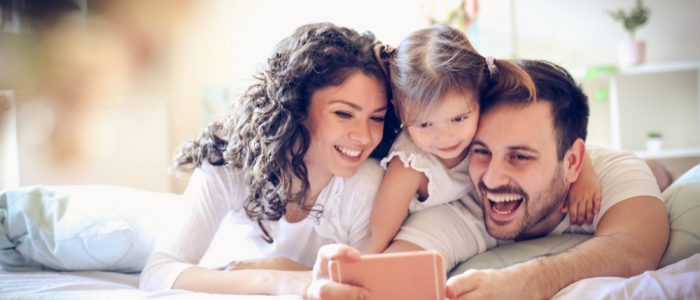Young family smiling and laughing and looking at their phone together